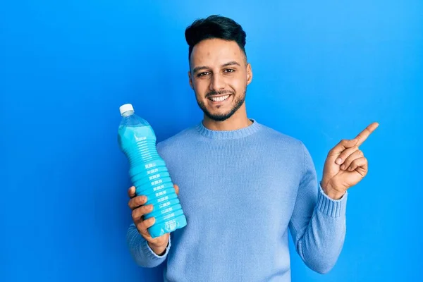 Young Arab Man Holding Detergent Bottle Smiling Happy Pointing Hand — Stockfoto