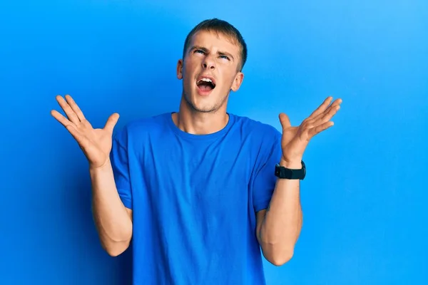 Młody Biały Mężczyzna Ubrany Luźną Niebieską Koszulkę Świętujący Sukces Podniesionymi — Zdjęcie stockowe