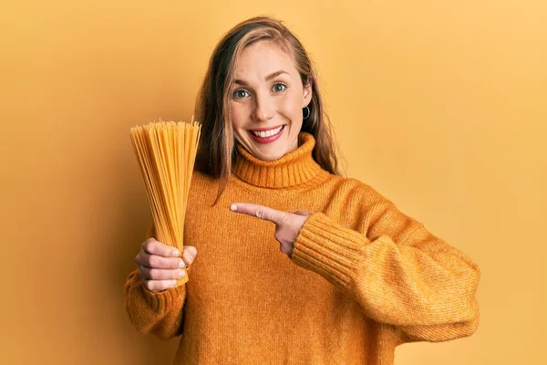 Young Blonde Woman Holding Dry Spaghetti Smiling Happy Pointing Hand — Foto Stock