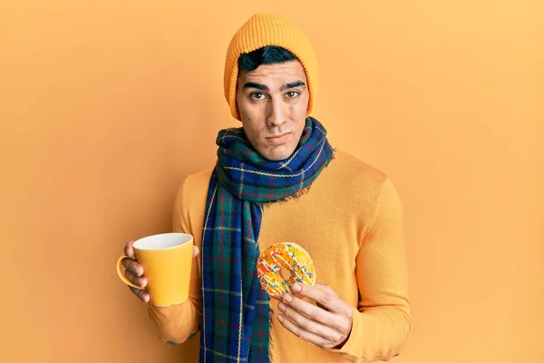 英俊而惊慌的男人吃着甜甜圈 喝着怀疑和紧张的咖啡 皱着眉头因为问题而烦恼 消极的人 — 图库照片