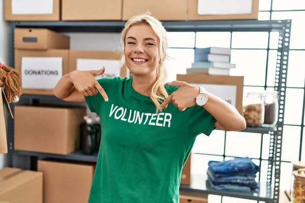 Gülümseyen Genç Sarışın Kız Hayır Kurumunda Gönüllü Üniformayı Göstermek Için — Stok fotoğraf