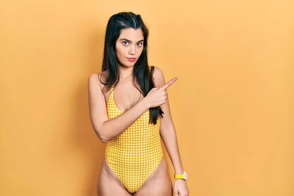 Young Hispanic Girl Wearing Swimsuit Pointing Hand Finger Side Showing — Stockfoto