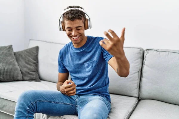 Νεαρός Ισπανόφωνος Χαλαρώνει Καθισμένος Στον Καναπέ Φορώντας Ακουστικά Στο Σπίτι — Φωτογραφία Αρχείου