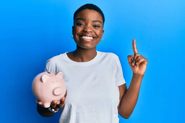 Young African American Woman Holding Piggy Bank Smiling Idea Question — Foto Stock