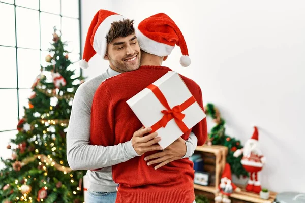 Two Hispanic Men Couple Surprise Gift Standing Christmas Tree Home — Stock Photo, Image