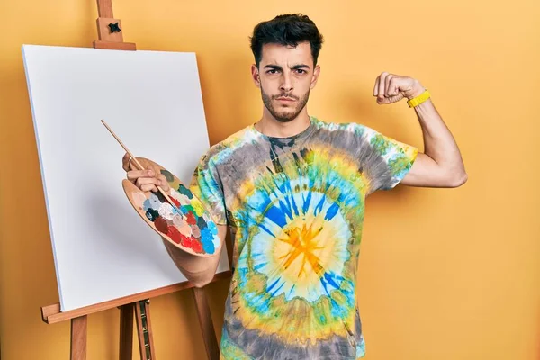 画家のイーゼルによるパレットで描かれた若いヒスパニック系の男は 腕の筋肉を示す強い人を立ちます 自信と力の誇り — ストック写真