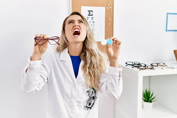 Young Beautiful Optician Woman Holding Glasses Contact Lenses Angry Mad — Fotografia de Stock