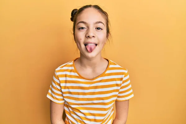 美丽的黑发小女孩穿着休闲的条纹T恤 带着滑稽的表情伸出舌头 情感概念 — 图库照片