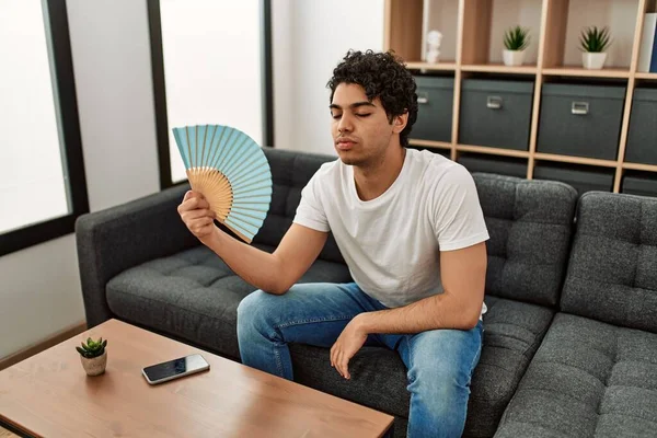 Young Hispanic Man Using Hand Fan Sitting Sofa Home — Stock Photo, Image