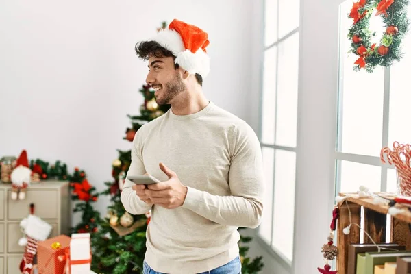 Joven Hombre Hispano Usando Sombrero Navidad Usando Smartphone Casa — Foto de Stock