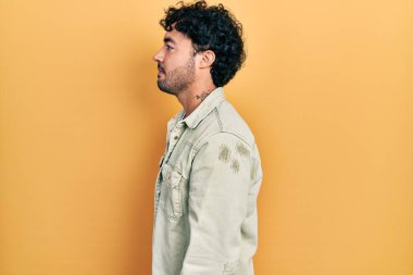 Latin kökenli genç adam rahat bir görünüm takınıyor, rahat bir görünüm takınıyor, kendine güvenen bir gülümsemeyle.. 