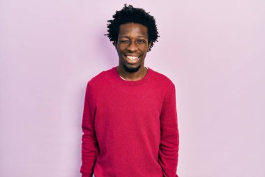 Genç Afro-Amerikalı sıradan kıyafetler giymiş, kameraya seksi bir ifadeyle bakıyor, neşeli ve mutlu bir yüzle.. 