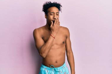 Young african american man with beard wearing swimsuit bored yawning tired covering mouth with hand. restless and sleepiness. 