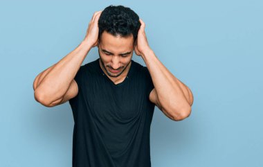 İspanyol sakallı, sıradan siyah tişörtlü, baş ağrısı çeken çaresiz ve stresli bir adam. Ağrı ve migren yüzünden. Eller başının üstünde.. 