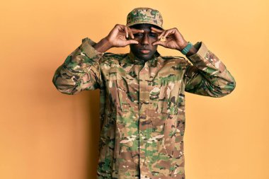 Young african american man wearing army uniform trying to open eyes with fingers, sleepy and tired for morning fatigue 