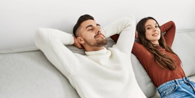 Genç İspanyol çift evde kanepede elleri üzerinde dinleniyor..