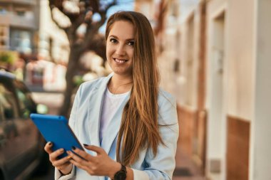 Şehirde dokunmatik ped kullanan genç sarışın iş kadını..