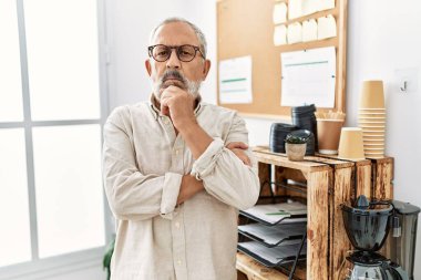 Senior grey-haired man standing with arms crossed gesture at office