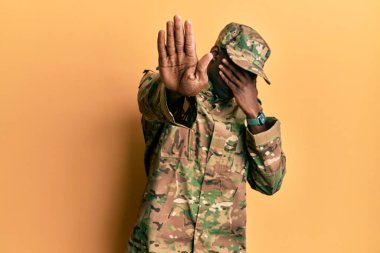 Young african american man wearing army uniform covering eyes with hands and doing stop gesture with sad and fear expression. embarrassed and negative concept. 