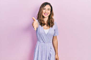 Gündelik kıyafetler giyen genç İspanyol kız dostça bir selamlama ve hoş geldin hediyesi olarak el sıkışmayı sunuyor. başarılı iş. 