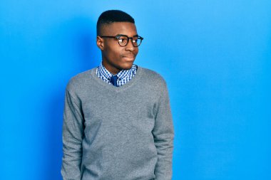 İş stili ve gözlük takmış genç Afro-Amerikan bir adam yüzünde gülümseme, doğal bir ifade ile diğer tarafa bakıyor. Kendinden emin gülen. 