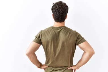 İspanyol bir adam izole edilmiş beyaz arka planda dikiliyor geriye bakıyor kolları vücudunda. 