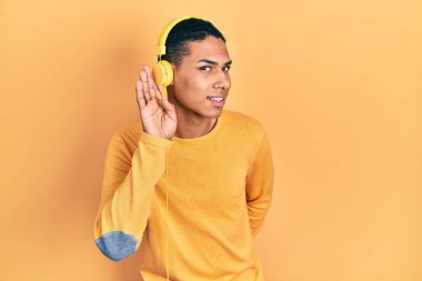 Genç Afrikalı Amerikalı adam kulaklıkla müzik dinliyor. Kulağından kulaklıkla gülümsüyor. Dedikoduları ve dedikoduları dinliyor. Sağırlık kavramı. 