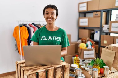 Genç İspanyol kadın gönüllü üniforması giyiyor. Yardım merkezinde çalışan bir dizüstü bilgisayar kullanıyor.