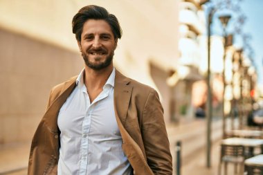 Genç İspanyol işadamı gülümseyerek şehirde mutlu mesut duruyor..