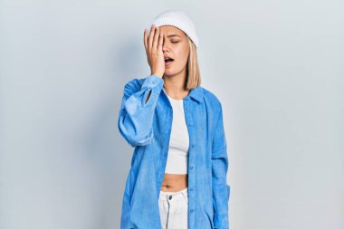 Güzel sarışın kadın yün şapka takıyor. Yarı yüzünü, göz ve ağzını eliyle kapatmaktan yorulmuş. Yüzüm acıyor.. 