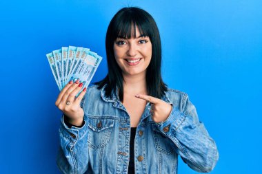 Bangladeş 'i tutan genç İspanyol kadın, gülümseyen banknotlar, mutlu bir şekilde elini ve parmağını işaret ediyor. 