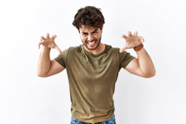 İzole edilmiş beyaz arka planda duran İspanyol bir adam komik bir şekilde kedi gibi pençe hareketi yapıyor, saldırgan ve seksi bir ifade. 