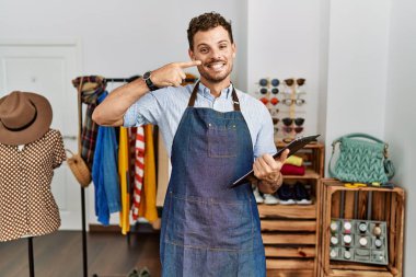 Handsome young man working as manager at retail boutique pointing with hand finger to face and nose, smiling cheerful. beauty concept 