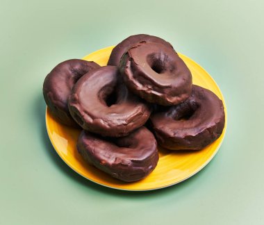  Plate of chocolate doughnuts over green background
