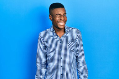 Genç Afro-Amerikalı sıradan kıyafetler giymiş, kameraya seksi bir ifadeyle bakıyor, neşeli ve mutlu bir yüzle.. 