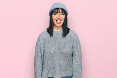 Şirin yün şapkalı genç İspanyol kadın komik bir ifadeyle mutlu bir şekilde dilini dışarı çıkarıyor. duygu kavramı. 