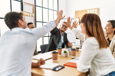 Group of business workers smiling happy celebrating high five at the office.