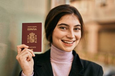 Genç ve güzel iş kadını gülümseyerek şehirde İspanya pasaportu taşıyor..