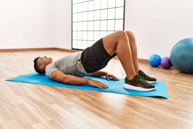 Genç İspanyol adam gülümsüyor spor merkezinde esniyor.