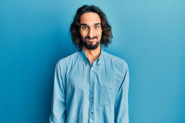 Günlük kıyafetler giyen genç İspanyol adam komik yüzlü yanakları şişiriyor. Havayla şişmiş ağız, çılgın bir ifade.. 