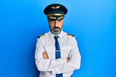 Sakallı, gri saçlı, uçak pilotu üniforması giyen, kuşkucu ve gergin orta yaşlı bir adam. Yüzünde çapraz kollarla onaylanmayan bir ifade var. negatif kişi. 