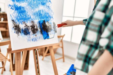 Resim stüdyosunda boya silindiri kullanan ressam kız öğrenci..
