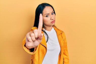 Burnu delinmiş, sarı deri ceketli, güzel İspanyol bir kadın parmağını kaldırmış ve kızgın bir ifade takınıyor. 