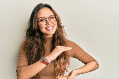 Gündelik kıyafetler giyen ve elleri büyük ve büyük boy işareti olan gözlüklü genç İspanyol kız. Ölçü sembolü. Kameraya bakıp gülümsüyor. ölçüm kavramı. 