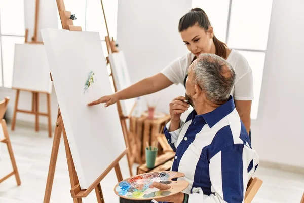 在艺术工作室 年轻的绘画教师妇女在画布上教老年男子绘画 — 图库照片
