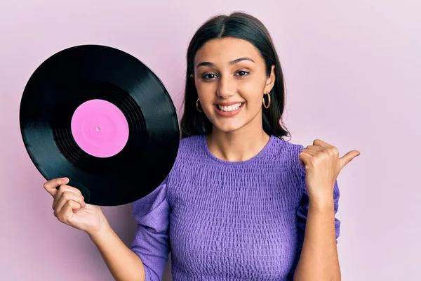 Ung Latinamerikansk Kvinna Håller Vinylskiva Pekar Tummen Upp Till Sidan — Stockfoto