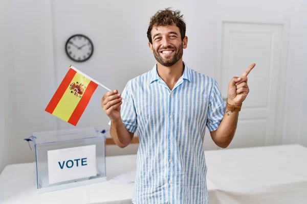年轻英俊的男子在政治选战中举着西班牙国旗 满面笑容 手指手画脚地站在一边 — 图库照片