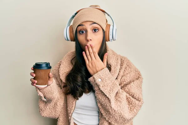Young Hispanic Woman Using Headphones Drinking Coffee Covering Mouth Hand — Zdjęcie stockowe