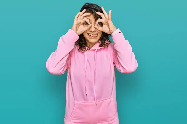 Young Hispanic Woman Wearing Casual Sweatshirt Doing Gesture Binoculars Sticking —  Fotos de Stock