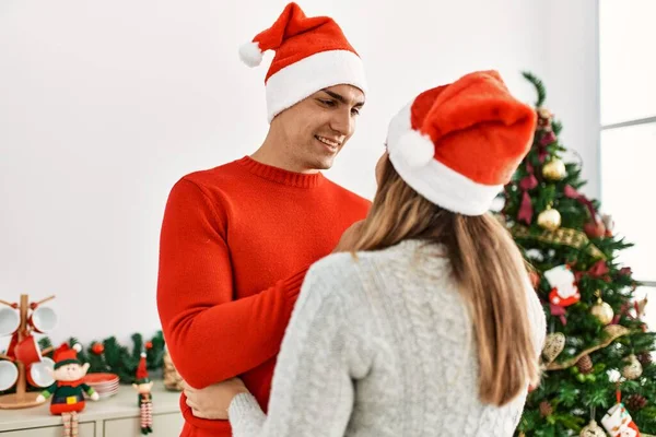 Genç Çift Kucaklaşıyor Gülümsüyor Evde Noel Şapkası Takıyorlar — Stok fotoğraf